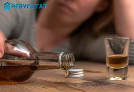 Женщина за столом с бутылкой в руке
