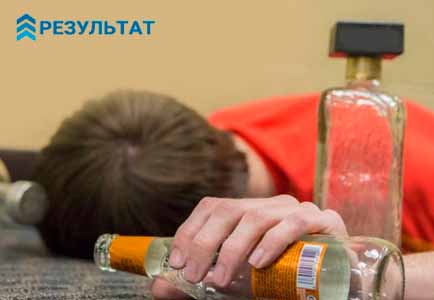 Алкоголик спит на полу рядом с бутылками